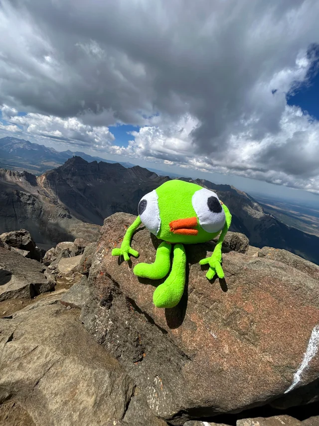 Green plush toy on a mountain